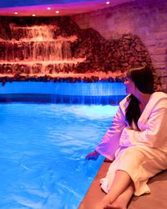 卡萨布兰卡艺术宫Spa套房酒店的坐在游泳池前的女人