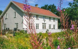 法尔松Lovely Home In Farsund With Wi-fi的白色的房子,有红色的屋顶和一些花
