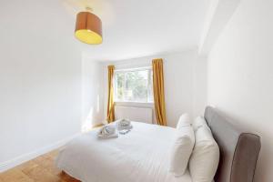 伦敦Cozy 3 bedroom apartment in Brixton的窗户客房内的一张带白色枕头的床