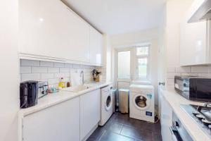 伦敦Cozy 3 bedroom apartment in Brixton的白色的厨房配有洗衣机和烘干机