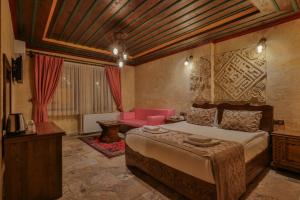 格雷梅Feel Cappadocia Stone House的一间卧室配有一张大床和一张粉红色的沙发