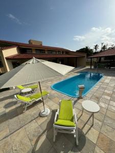 SirinhaémCasa aconchegante em Guadalupe/PE的一个带椅子和遮阳伞的庭院和一个游泳池