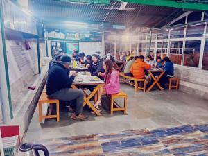 穆索里Himalayas Youth Hostel Kempty Mussoorie的一群坐在餐厅桌子上的人