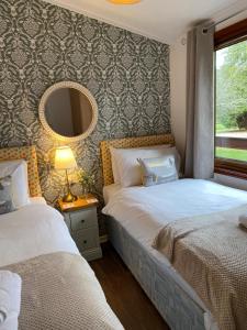 巴洛赫Walled Garden Lodges Loch Lomond的一间卧室配有两张床和镜子
