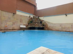 齐克拉约GLORIA PLAZA HOTEL的一座大型游泳池,在一座建筑中设有喷泉