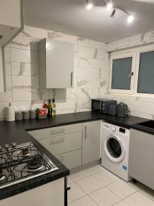 伦敦Well-preserved cozy1BR flat in LCY with free parking的厨房配有炉灶和洗衣机。