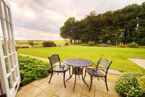亨斯坦顿赫奥叉姆玛诺酒店的庭院设有桌椅和草坪
