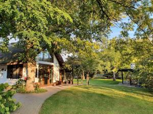 基什孔毛伊绍Cottage im Natur-Resort Pool, Schwimmteich & Sauna的草场旁有树的建筑