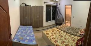 拉合尔Magnum Girls Hostel的小房间设有两张床和一个衣柜