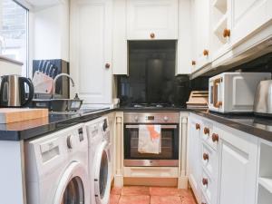 Luddenden FootVintage Cottage的厨房配有白色橱柜、洗衣机和烘干机