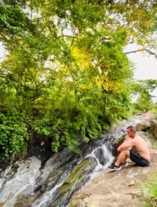 阿瓜斯迪林多亚Aconchego na montanha com BANHEIRA de imersão e 5 suítes 7,5km do centro Águas de Lindóia的坐在瀑布旁的岩石上的人