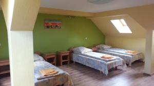 Tāšu-PadureSpāres的一间设有三张床的客房,位于带绿色墙壁的房间