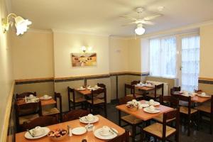 伦敦榆木酒店的餐厅配有桌椅和吊扇