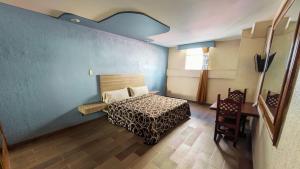 墨西哥城Hotel Plaza San Juan的一间卧室设有一张床和蓝色的墙壁