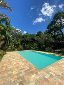 贝洛奥里藏特Casa de Campo Pampulha的一座游泳池,位于一个有树木和蓝天的院子内