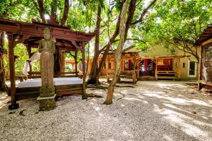 霍姆斯泰德Exotic Sukiya Tiny House Japanese Balinese Gardens的坐在树下床边的人的雕像