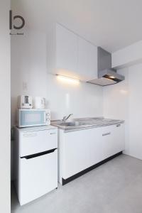 广岛bHOTEL Heiwaoodori - New Apt in Famous Hiroshima Dori Max 6p的白色的厨房配有水槽和微波炉