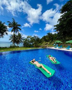 BuruangaTuburan Cove Beach Resort的两人在游泳池里躺在冲浪板上