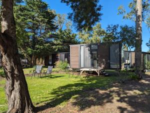 Dadswells BridgeTiny House 18 at Grampians Edge的树林中的小屋,配有野餐桌和椅子