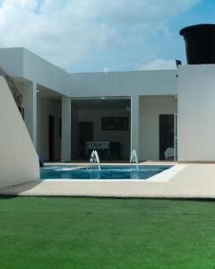 SabanagrandeCABAÑA LUJOSA CON MESA DE BILLAR的白色的房子,设有游泳池和喷泉