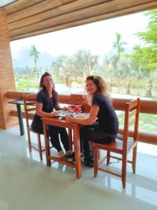 万荣Vang Vieng Romantic Place Resort的两个女人坐在房间里桌子上