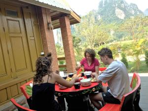 万荣Vang Vieng Romantic Place Resort的一群人坐在庭院的桌子旁