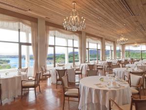 志摩市志摩观光经典酒店的宴会厅配有白色的桌椅和窗户