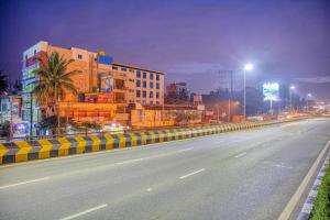 班加罗尔Redkey Transit Hotel Near Bangalore Airport的一条空荡荡荡的街道,晚上有建筑物和街灯