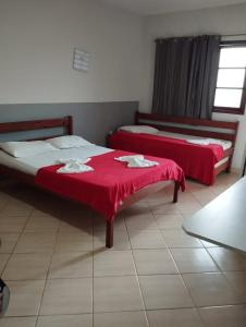 瓜拉派瑞Pousada Em Guarapari - Pousada Paraiso的红色床单的客房内的两张床