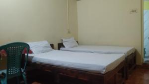 阿姆波尔Laxmi Guest House (Arambol Beach)的配有椅子的客房内的两张单人床