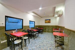新德里Hotel Grand Qubic Near Delhi Airport的餐厅设有红色的桌椅和平面电视。