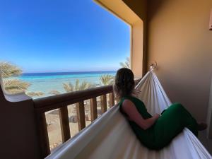 赫尔格达索马湾破浪者潜水与冲浪酒店的坐在阳台上的女人,从阳台上望出大海