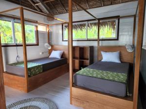 Tua PejatLeleu Mentawai Accommodation的带窗户的客房内的两张床