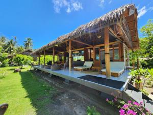 Tua PejatLeleu Mentawai Accommodation的茅草屋顶和花园别墅