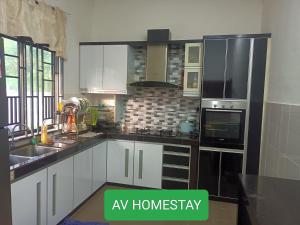 关丹AV HOMESTAY的厨房配有白色橱柜和黑色家电