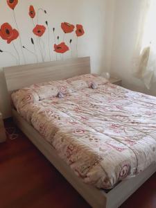 米兰La Casa di Boh, vicino ospedale San Paolo, Iulm, Forum Assago的卧室里的一张床铺,墙上挂着红色的鲜花