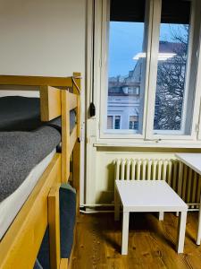 诺维萨德Hostel Stari Grad的客房设有床、桌子和2扇窗户。