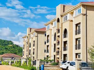 KigoFully furnished 3 bedroom apartment in Mirembe Villas Kigo, Uganda的前面有停车位的建筑