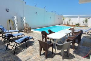 贝贾亚ILY House : Villa de plage avec piscine sans vis-à-vis.的游泳池旁带桌椅的天井