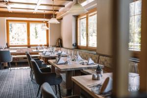 奥贝雷根Hotel Mont Floris Obereggen的餐厅设有木桌、椅子和窗户。