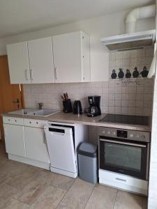 格赖夫斯瓦尔德Emma的厨房配有白色橱柜和炉灶烤箱。