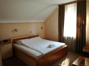 图兹拉Motel Royal的一间卧室配有一张带白色床单的床和一扇窗户。