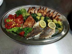 图兹拉Motel Royal的桌上一盘带鱼和蔬菜的食物