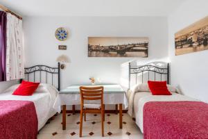 塞维利亚特里亚纳洛斯雷梅迪奥斯公寓的一间卧室配有两张床和一张桌子及椅子