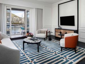开普敦Cape Grace, A Fairmont Managed Hotel的客厅配有电视、沙发和椅子