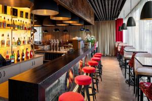 林茨Amedia Linz, Trademark Collection by Wyndham的餐厅内带红色凳子的酒吧