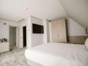 锡比乌Mercure Sibiu Arsenal的白色卧室配有白色的床和电视
