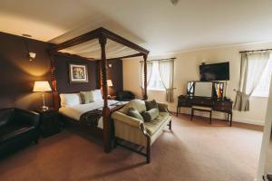 海布里奇The Grange Hotel Brent Knoll的一间卧室配有一张天蓬床、椅子和钢琴