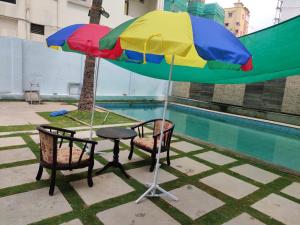商沙巴Rainbow International Hotel Airport Zone Shamshabad的游泳池旁遮阳伞下的桌椅