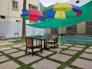 商沙巴Rainbow International Hotel Airport Zone Shamshabad的一张桌子,两把椅子和两把五彩缤纷的雨伞